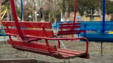 Lonely red empty deserted swing in an old abandoned amusement park. Swinging Stock Footage 151924325