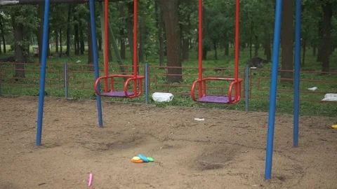 Lonely red empty deserted swing in an old abandoned amusement park. Swinging Stock Footage 155010627