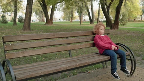 Lonely red-haired child sitting on bench in park, abandoned kid feeling upset Vídeo Stock 144316152