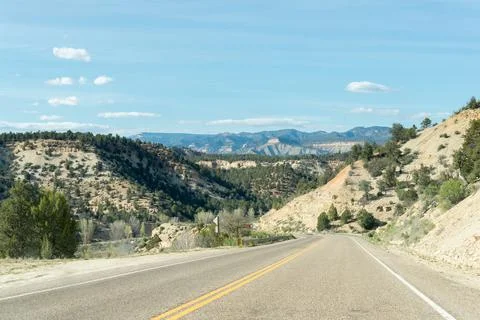 Lonely road between mountain ridges with some trees on each side of the road, Foto stock
