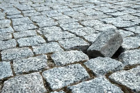 Lonely rock on a damaged cobblestone street in an old medieval city. Stock Photos