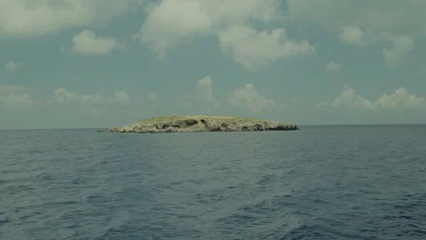 A lonely rocky island in the middle of the endless blue sea under a cloudy sky. Stock Footage 346717191