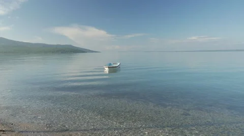 Lonely row boat floating on clear water with small waves in the morning. 4k Stock Footage 58482098