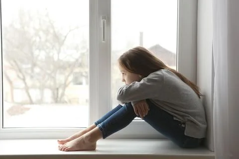 Lonely sad girl at home. saddened alarmed child alone at home. Stock Photos