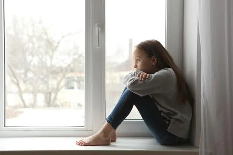 Lonely sad girl at home. saddened alarmed child alone at home. Stock Photos