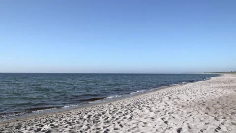 Lonely sandy beach on the baltic coast. Blue sky, bright sun. Small sea waves. Stock Footage 155098270