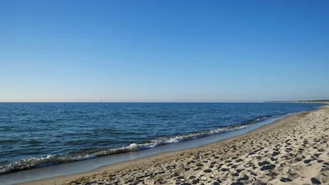 Lonely sandy beach on the baltic coast. Blue sky, bright sun. Small sea waves. Stock Footage 155280502