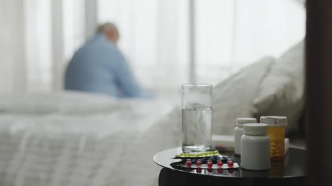 Lonely senior man sitting on nursing home bed, preparing to take medication Stock Footage 346484936