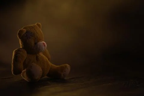 Lonely Teddy Bear in Dim Light Evoking Melancholy and Nostalgia on Wooden Flo Foto stock