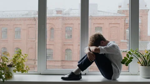 Lonely Teenage Boy Sitting on Windowsill Looking through Glass Stock Footage 337887853
