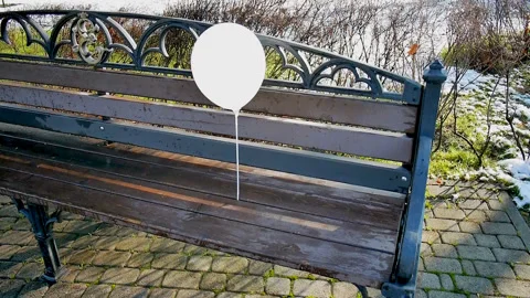 Lonely white balloon, left on a bench outside, swaying in the wind Stock Footage 85660964