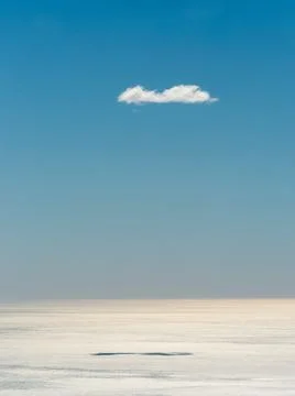 Lonely white cloud casts its shadow on the silvery sea Stock Photos