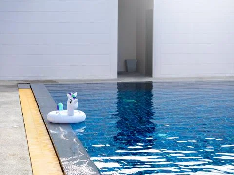The lonely white inflatable ring, cute unicorn doll in the outdoor swimming.. Stock Photos
