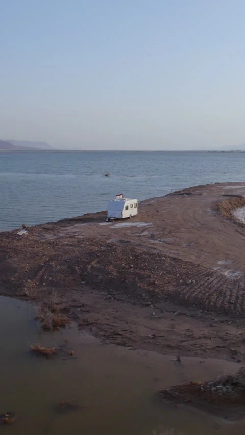 Lonely white trailer parked on one of the sand dikes separating the Dead Sea - Stock Footage 310674235