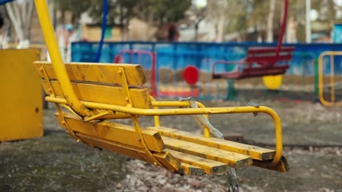 Lonely yellow empty deserted swing in an old abandoned amusement park. Swinging Stock Footage 151924322