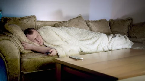 Lonely young man is lying on the couch watching TV at night, camera movement Video stock 163382661