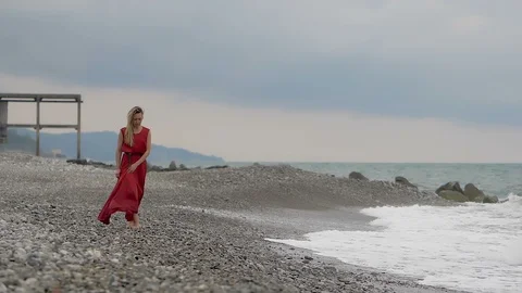 Lonely young woman walking on the beach with sea waves in background Stock Footage 94334953