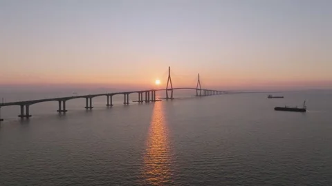 Long Aerial Take Passing Two Bridge Pylons With Ship Shadow at Sunset Stock Footage 344694397
