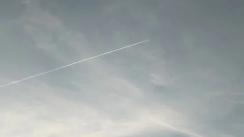 A long airplane trail in the blue cloudy sky Stock Footage 239647458