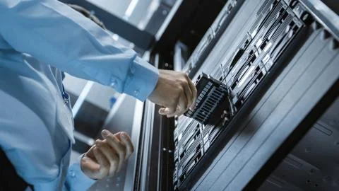 Long Angle Shot In Fully Working Data Center IT Engineer Installs Hard Drive  Stock Photos