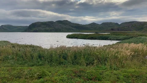 Long angle view: calm lake in front of low hills under clouds. Teriberka, Russia Stock Footage 232328294