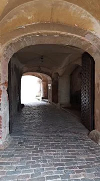 Long arch under the wall of the old castle and a paved stone road to drive th Stock Photos