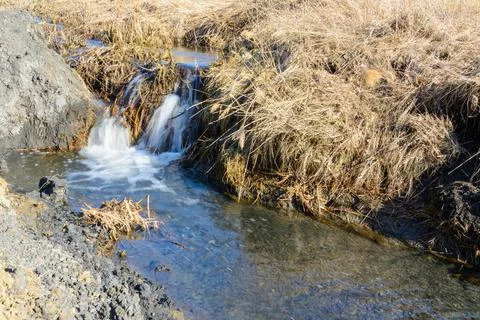 Long-awaited spring creeks flow over ravines and hills on a sunny day. Water  Stock Photos