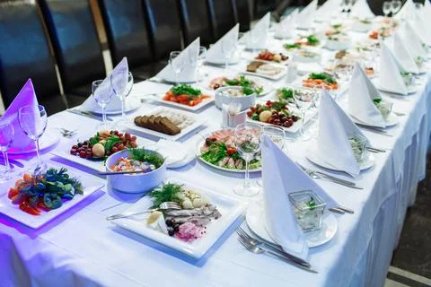 Long banquet table set with white tablecloth, folded napkins, and various Stock Photos
