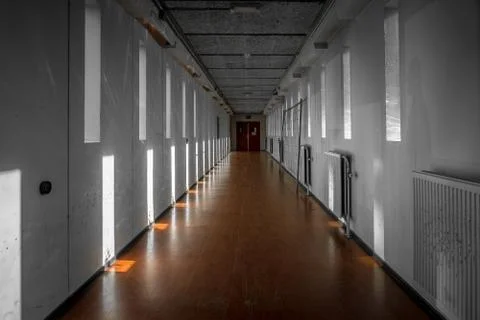 A long bare corridor with light and dark shadow spots. The corridor evokes an Stock Photos