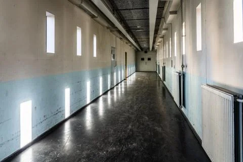A long bare corridor with light and dark shadow spots. The corridor evokes an Stock Photos