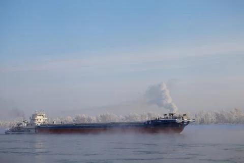 Long barge going down river in cold winter. Stock Photos