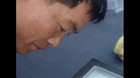 LONG BEACH - 1968 - A Korean sailor paints a hatch cover while another sailor Stock Footage 316680892