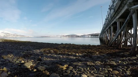 Long beautiful bridge with bright sunshine on blue sky with calm moving waves Stock Footage