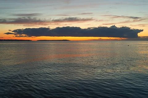 Long big dark cloud over the sea at sunset Stock Photos