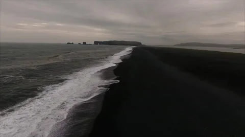 Long black shoreline running toward a distant arch headland Stock-Footage 64072365