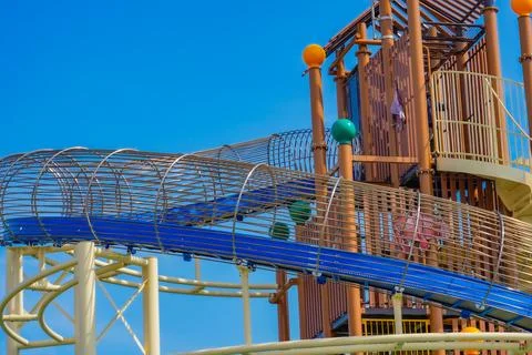 A long blue slide crossing a large playground structure. Stock Photos