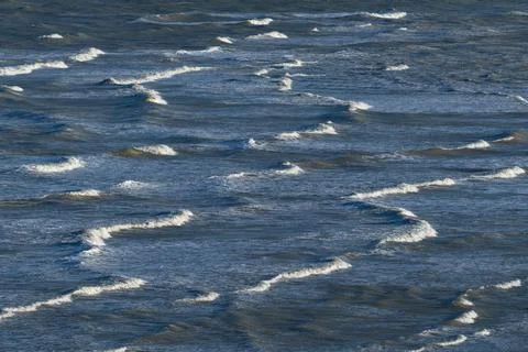 Long breaking waves on the shore with the white waves lit by the sun Stock Photos
