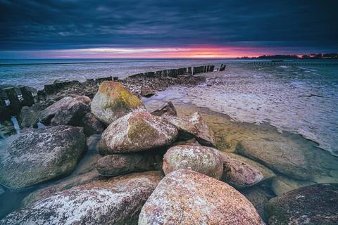 Long breakwater at cloudy sunset Stock Photos