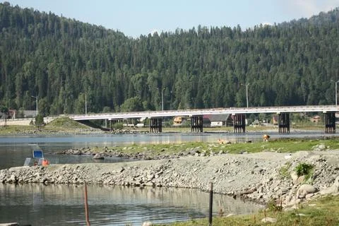 Long bridge over a mountain river leading to a forest hill village Stock Photos