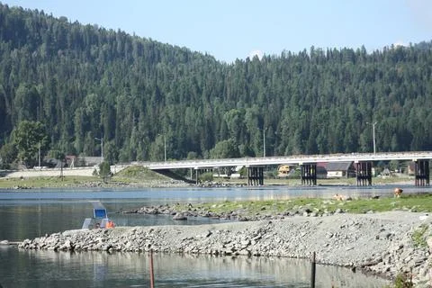 Long bridge over a mountain river leading to a forest hill village Stock Photos