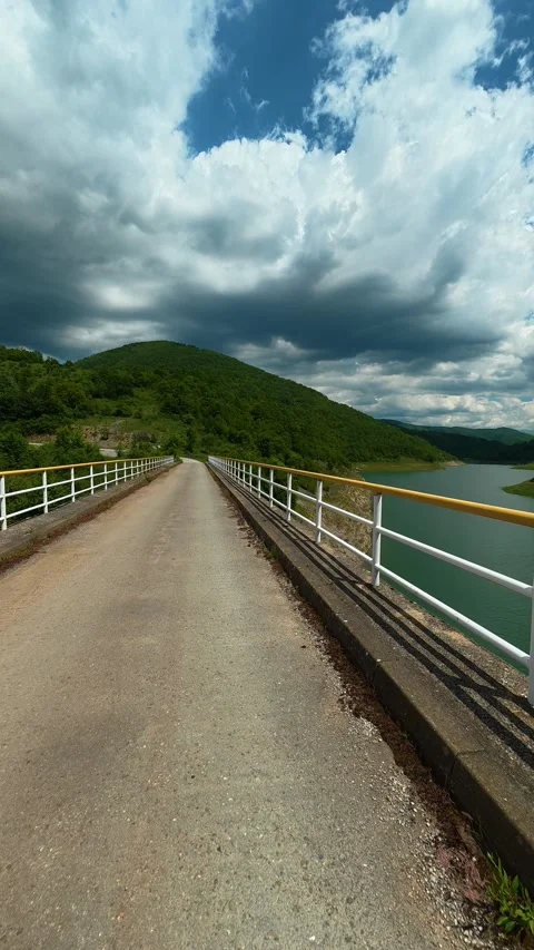 Long bridge spans tranquil green lake. Zavoj Lake, Serbia. Vertical Stock Footage 337495804
