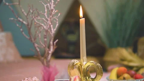 Long candle next to pink branch with fruit in the backround relaxing Stock Footage 194462104