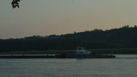A long cargo barge sails down a river during golden sunset Stock Footage 339629485