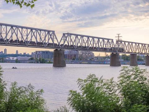 Long cargo train moving along the urban bridge over  Dnipro river in Kyiv Stock Photos