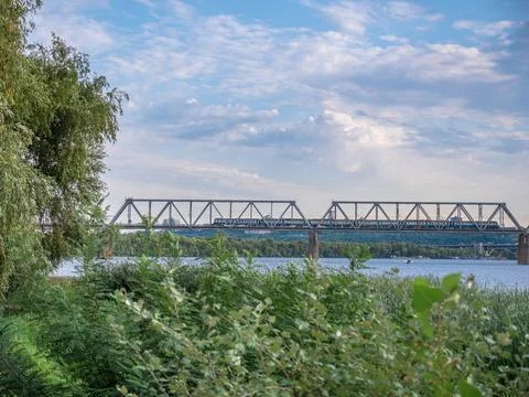 Long cargo train moving along the urban bridge over  Dnipro river in Kyiv, Uk Foto stock