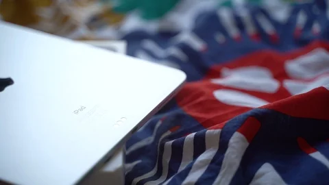 Long close-up shot of silver iPad Pro back lying on box, on bed, high angle Stock-Footage 129153905