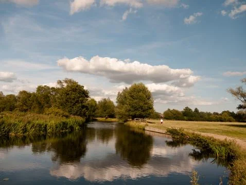 Long cloud and blue sky reflected in river with trees in the country lady wal Stock Photos