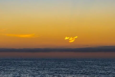 A long cloud over the ocean at sunset. Stock Photos