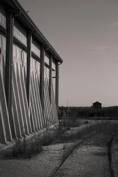 Long concrete wall with triangular supports and abandoned railway tracks in.. Stockfoto's