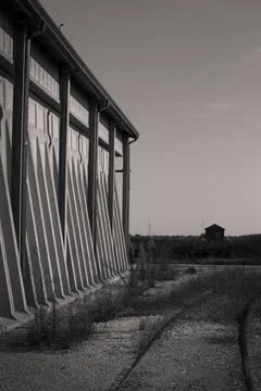  Long concrete wall with triangular supports and abandoned railway tracks ... Foto stock